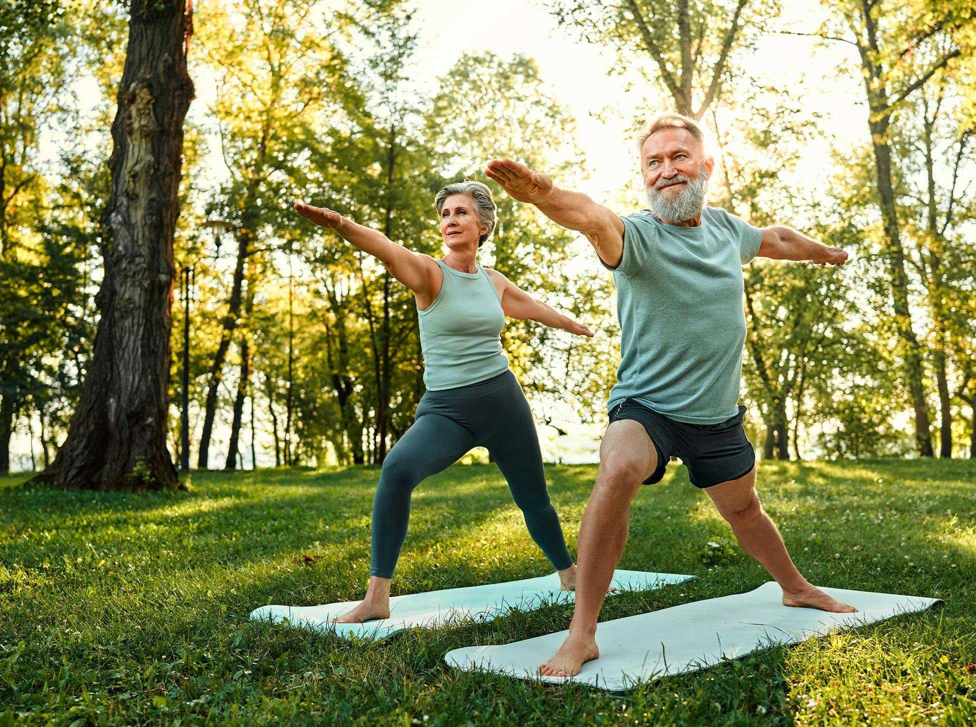 older man and woman doing yoga in a park