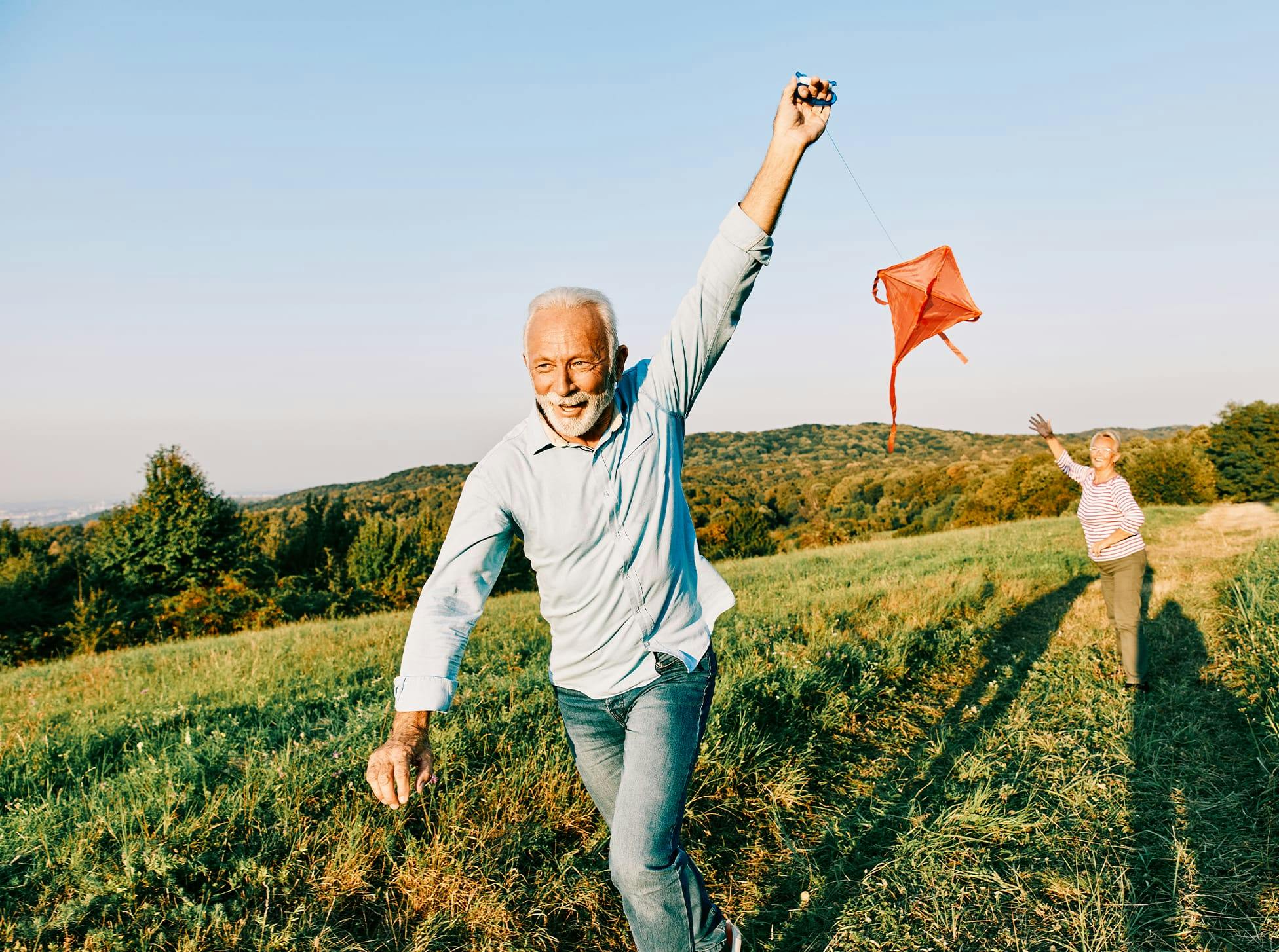 older man and woman flying a kite in a field