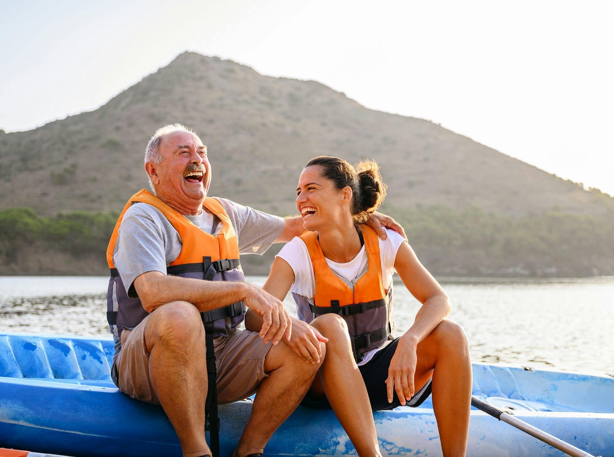 father and daughter sitting on a kayak on the shore, laughing