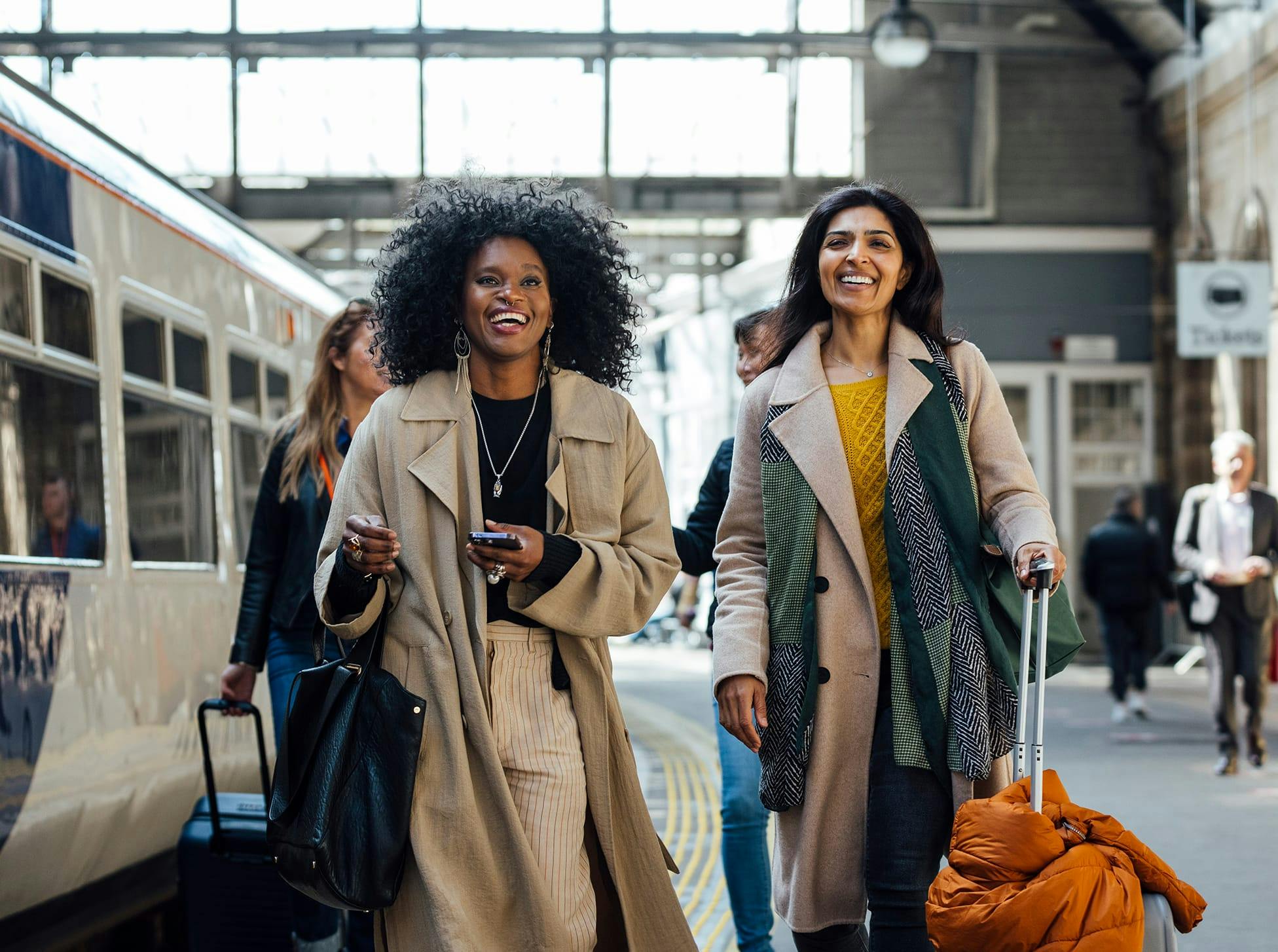 two women getting off a train with their luggage
