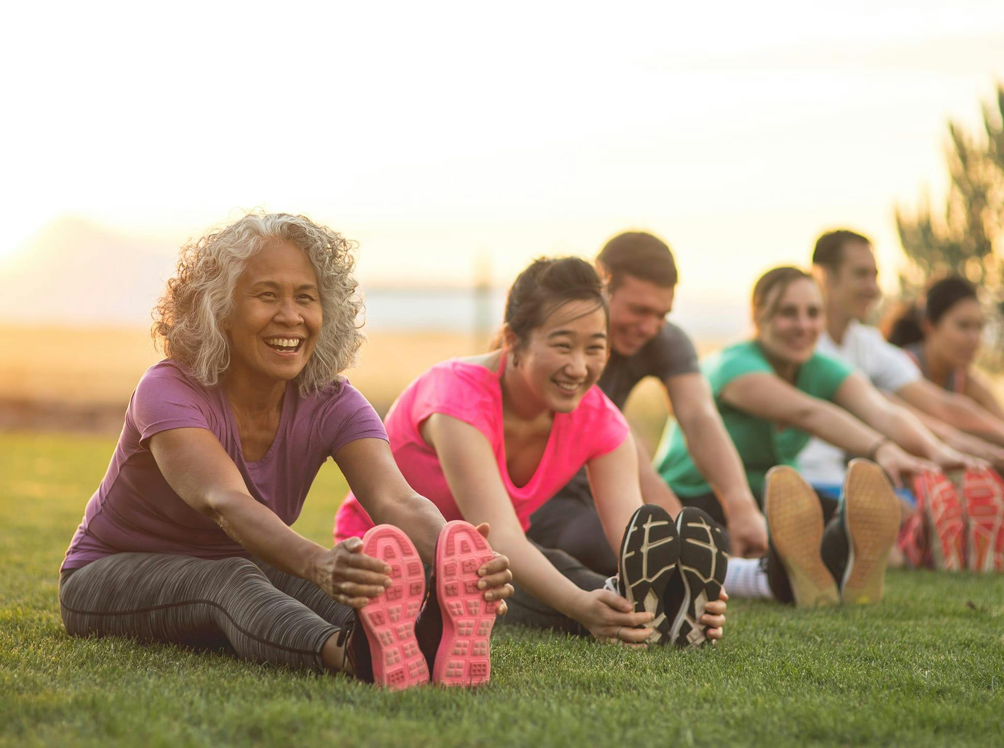 group of people stretching while sitting in grass