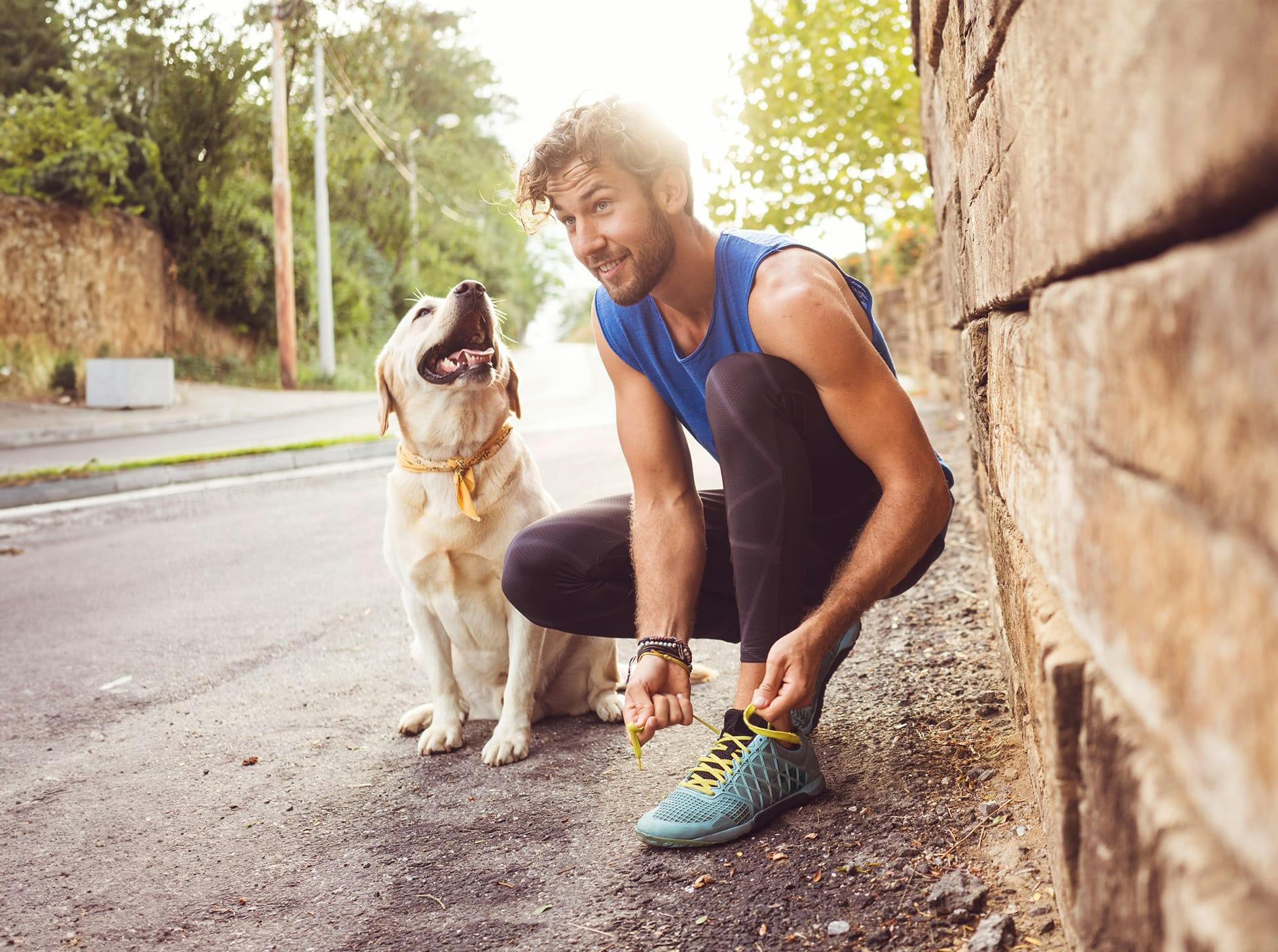 man tying his show, dog sitting next to him