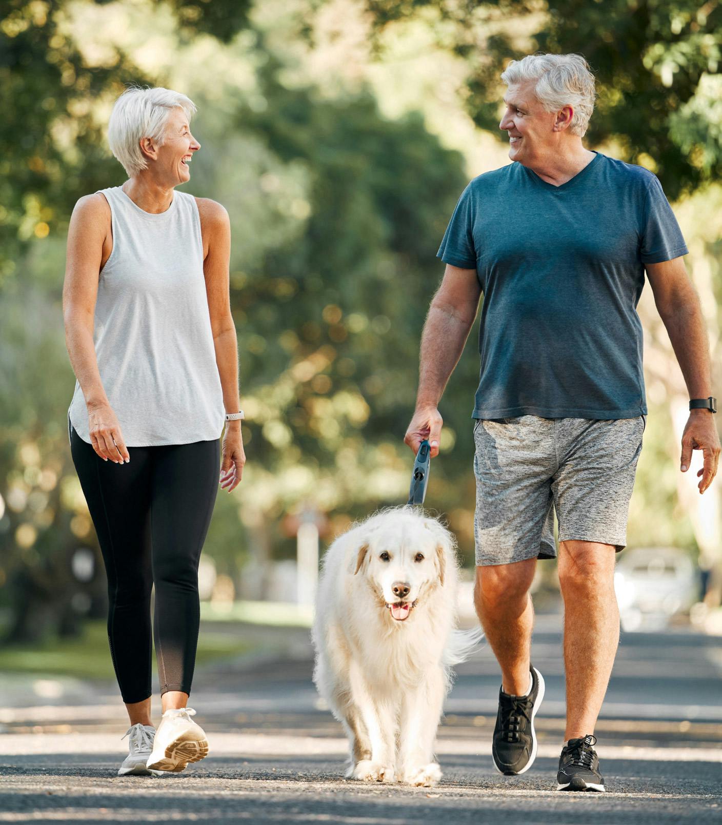 older couple walking a dog outside