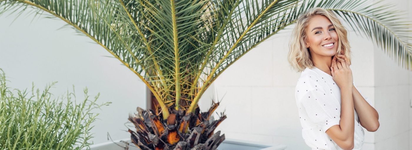 Blonde woman smiling near palm tree