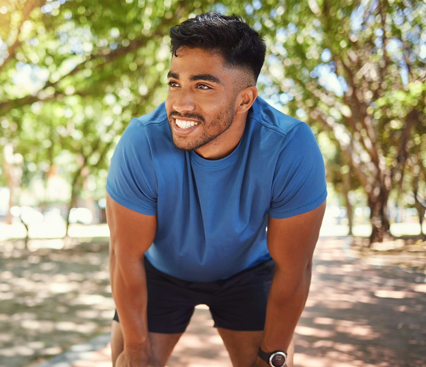 Athletic man smiling while resting outside