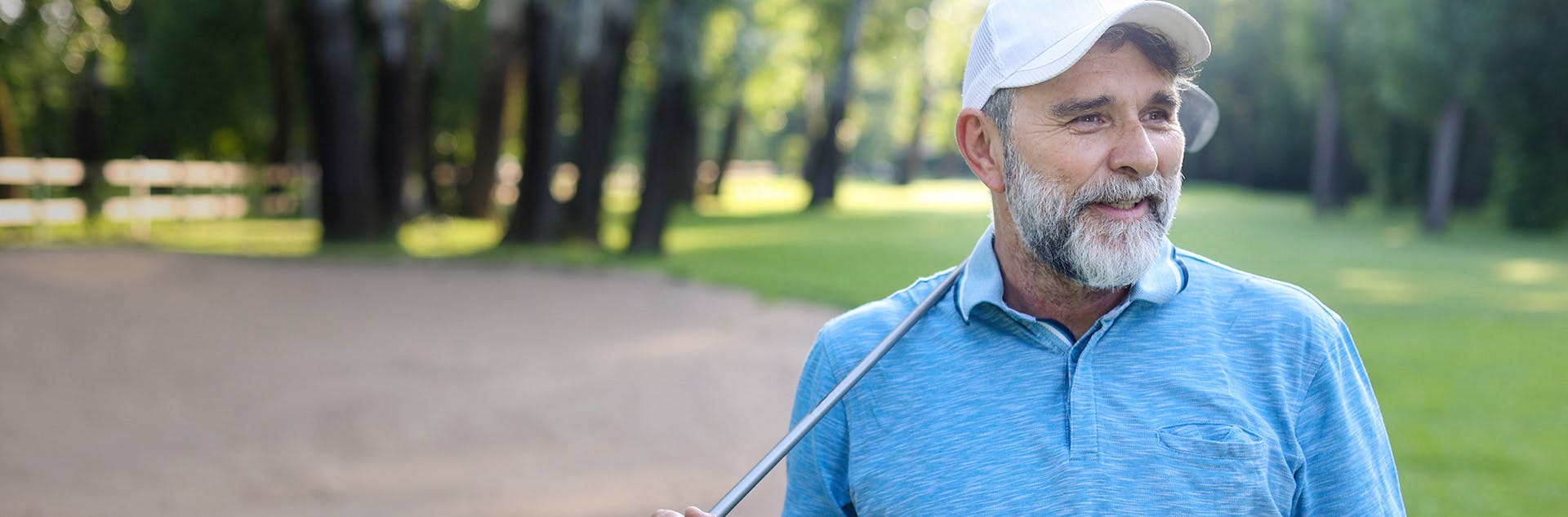 Older man holding a golf club smiling