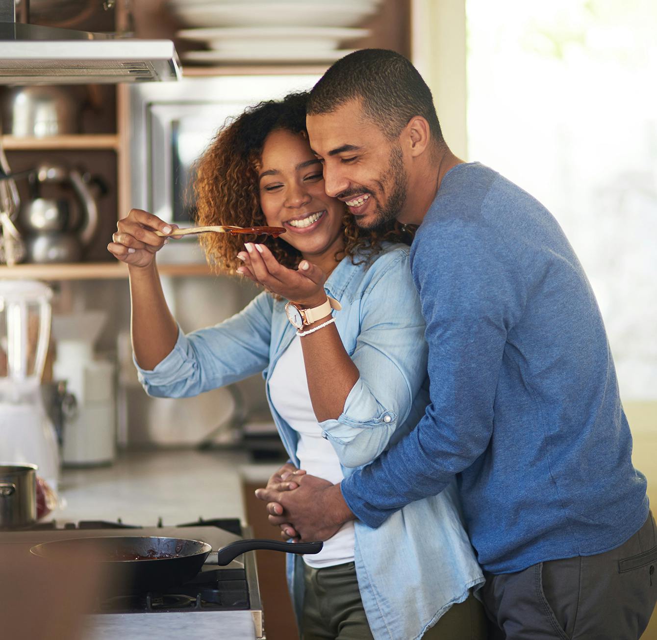 Man and woman in the kitchen tasting a sauce