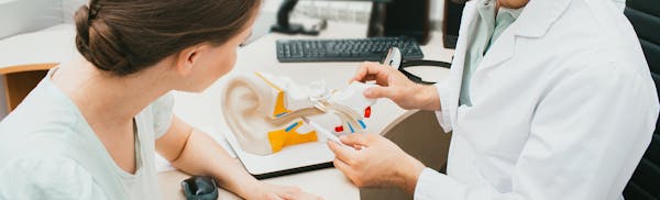woman looking at a diagram of an ear with a doctor