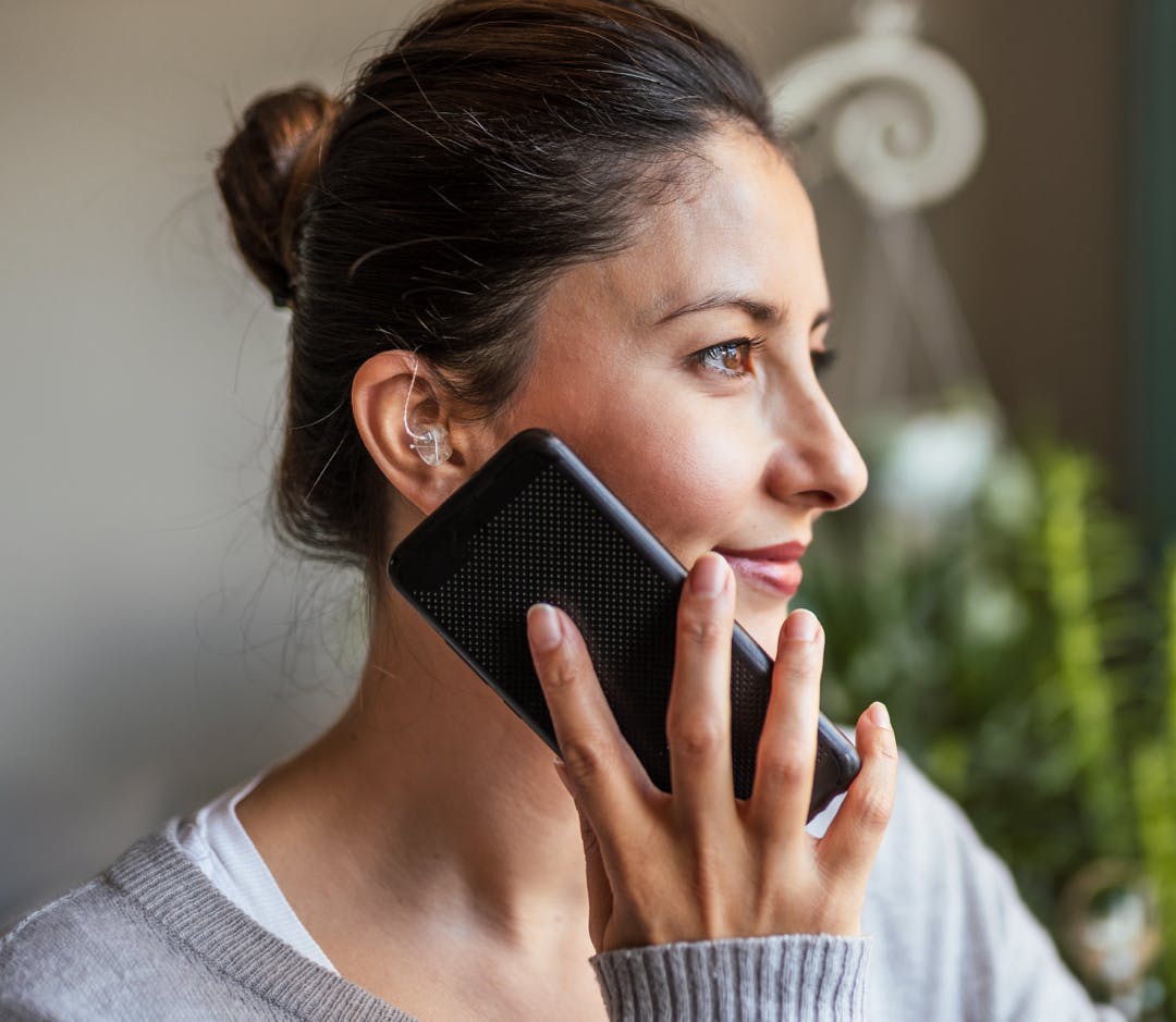 woman with hearing aid on phone