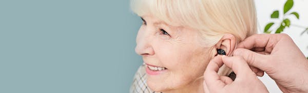 doctor fitting a hearing aid