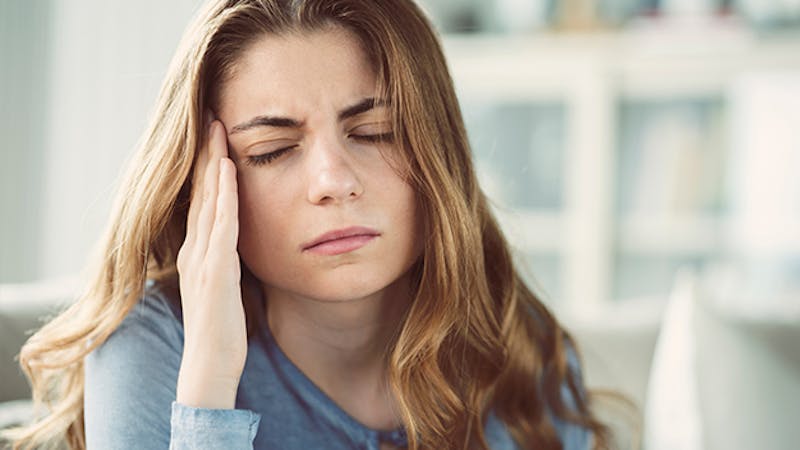 woman touching her head with her eyes closed