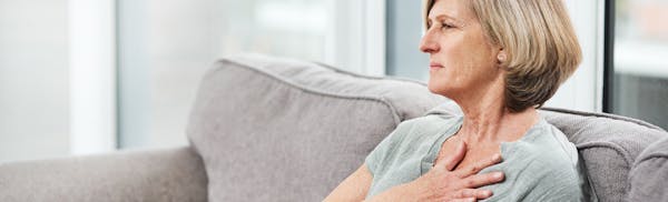 woman touching her chest in discomfort