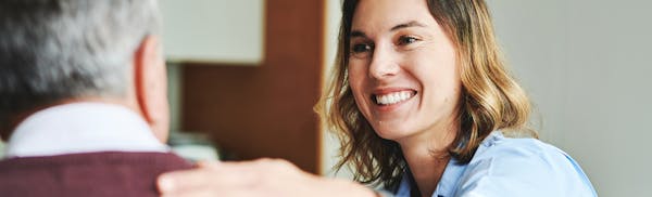 woman with shoulder length blonde hair touching a mans shoulder while smiling