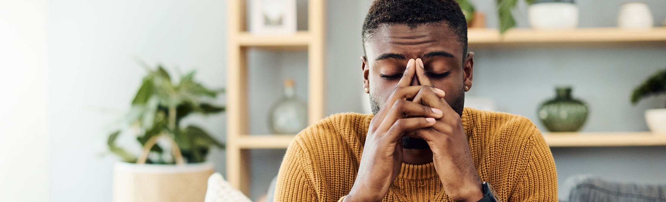 man resting his face on his hands in discomfort
