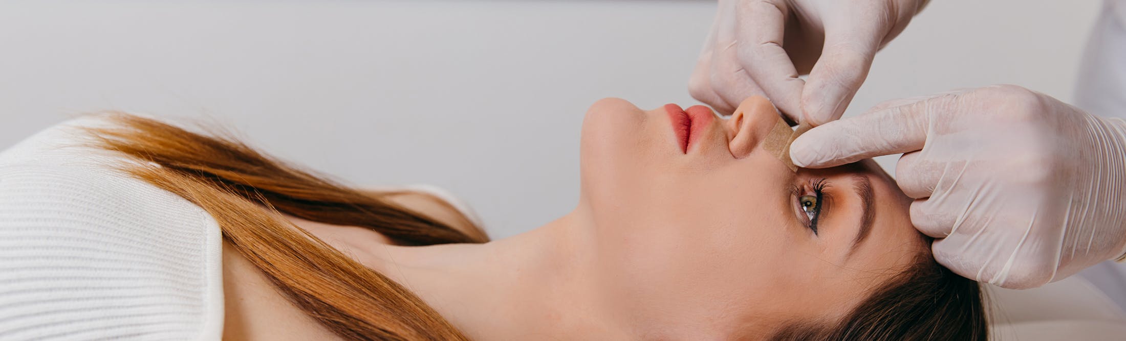 woman getting tape on her nose