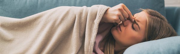 woman pinching the bridge of her nose in discomfort