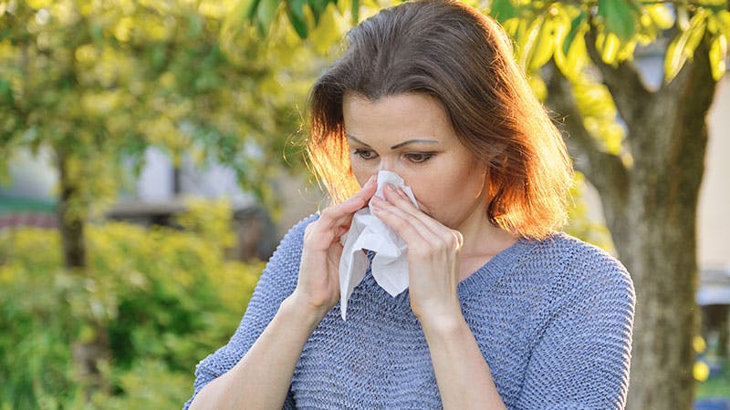Woman sneezing into a tissue