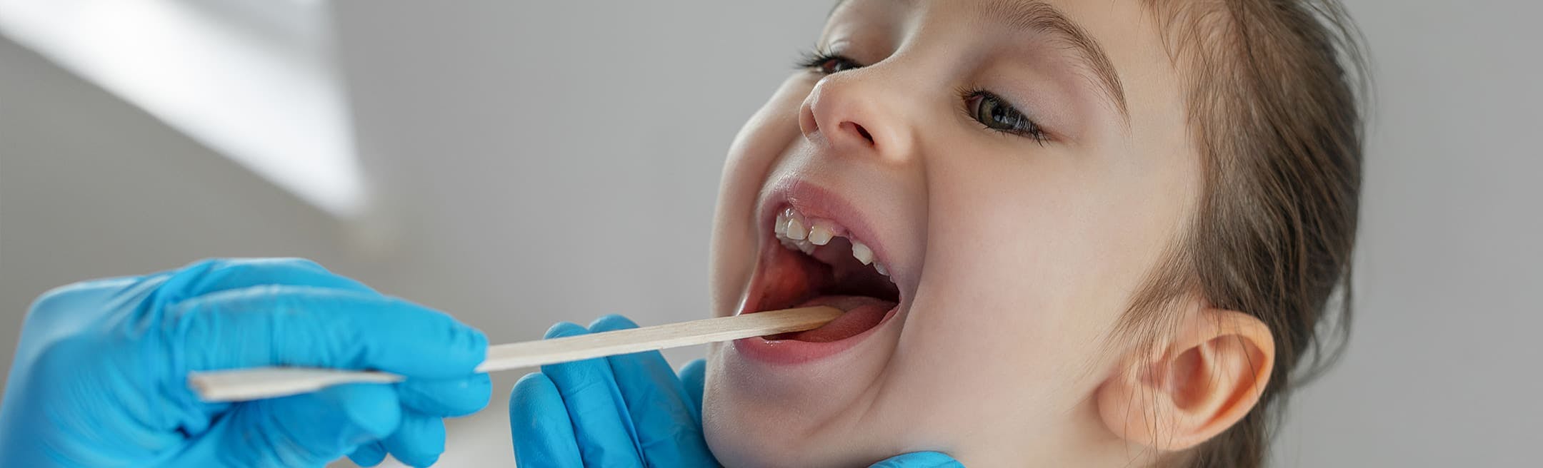 young girl having her throat inspected