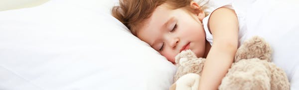 kid sleeping while holding a teddy bear