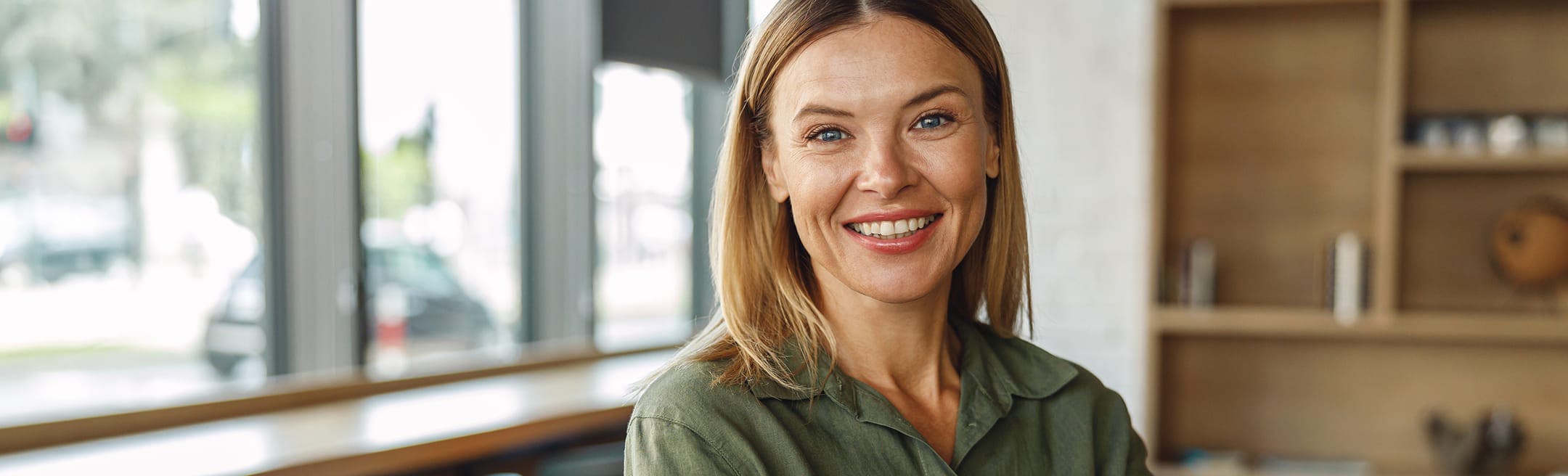 woman with blonde hair smiling while wearing a green top