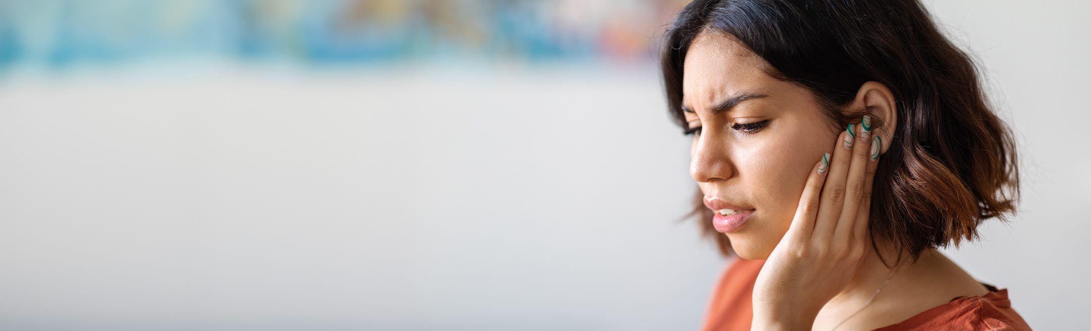 woman touching her ear while looking stressed