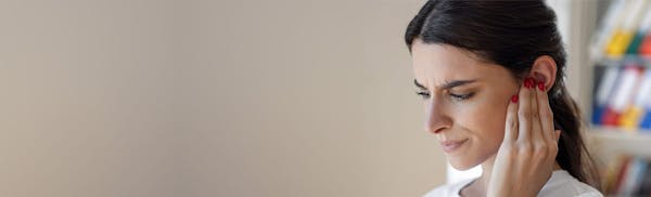 woman touching her ear while looking concerned