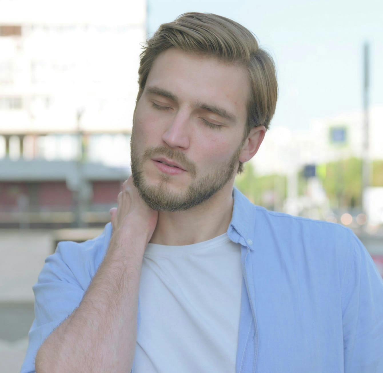 man touching his neck in discomfort