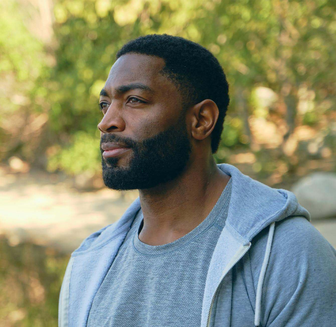 older man outside wearing a grey hoodie