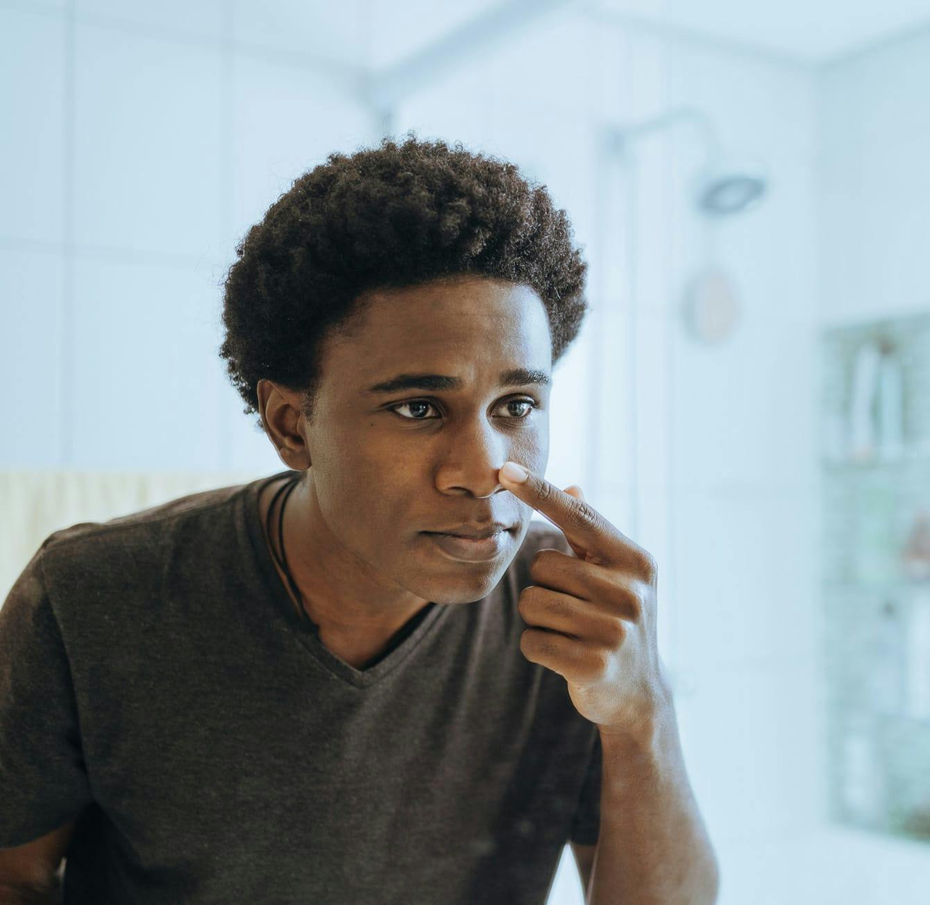 man looking at his nose in the mirror