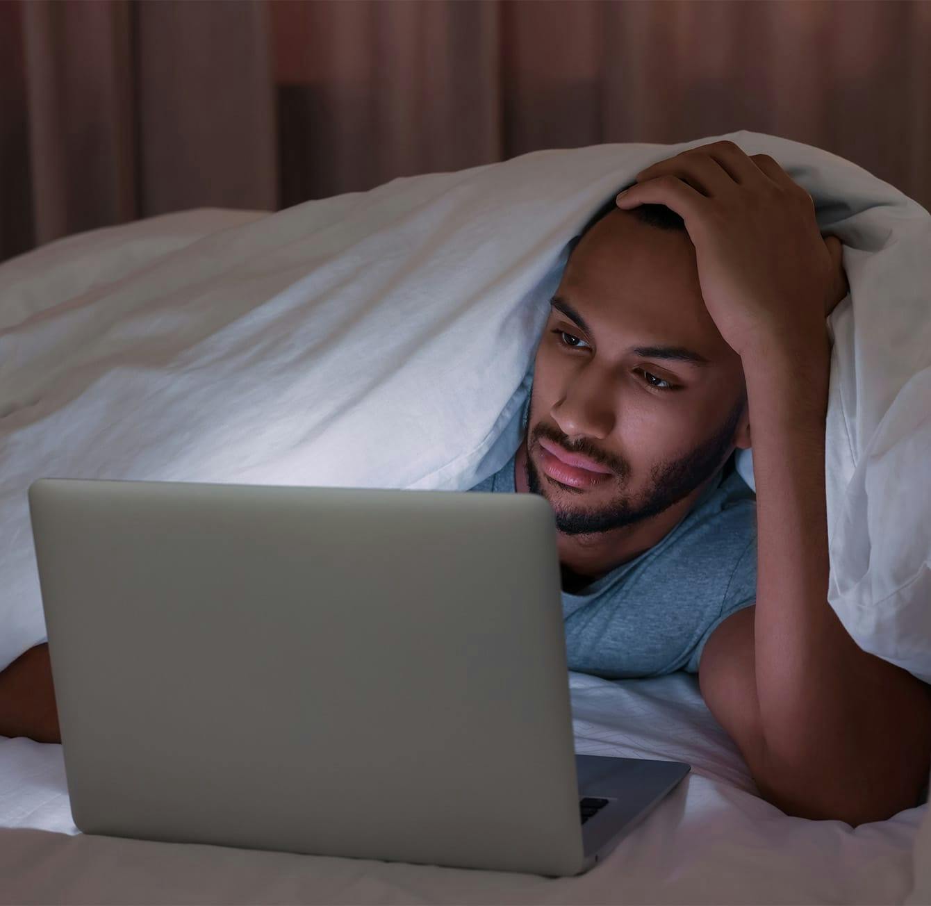 man laying in bed on a laptop