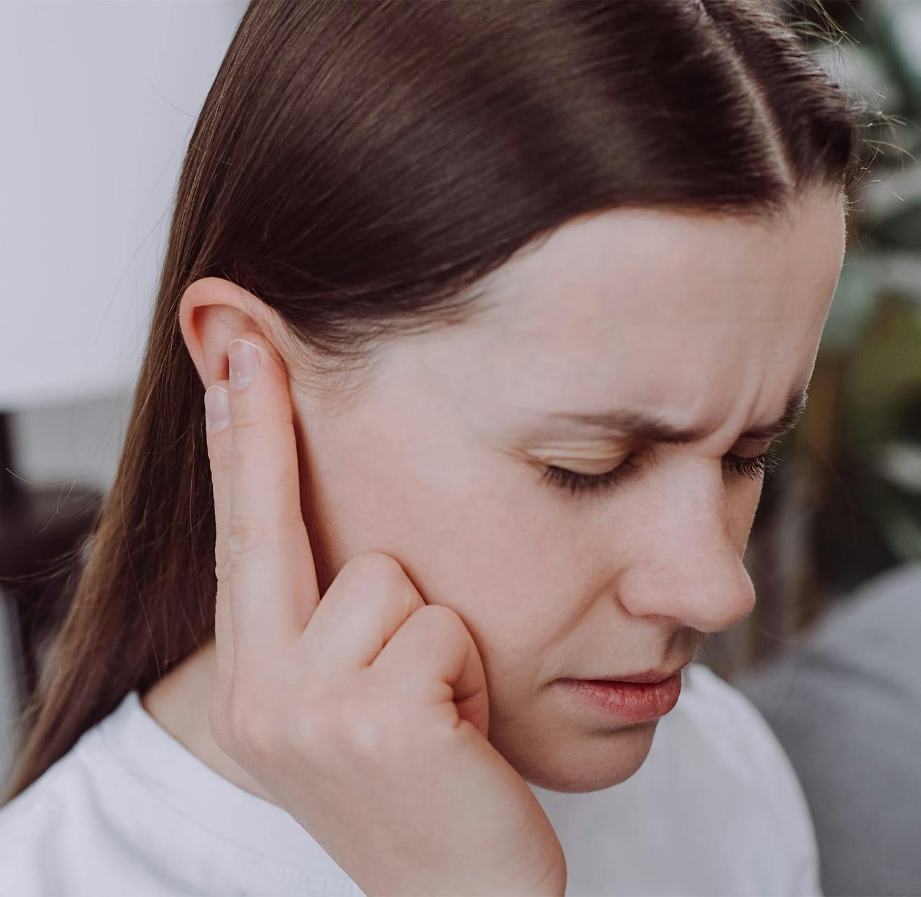 woman touching her ear while looking frustrated