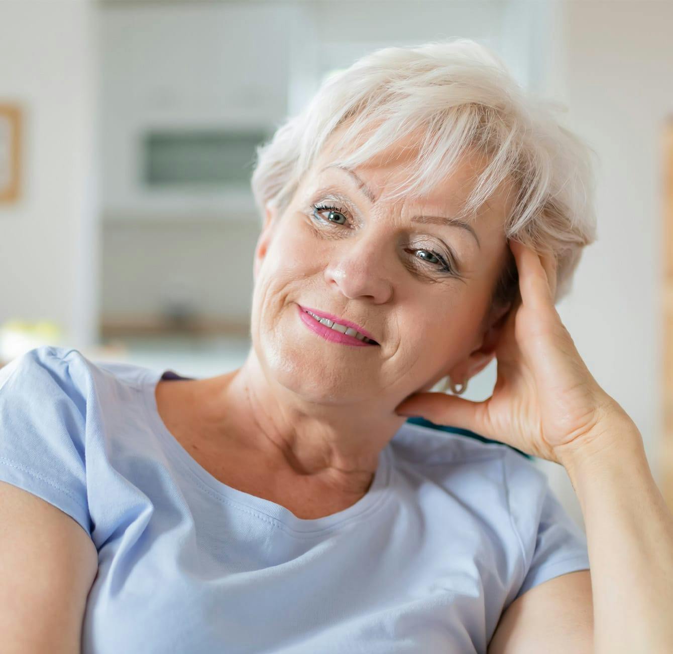 woman with very short grey hair wearing a blue shirt
