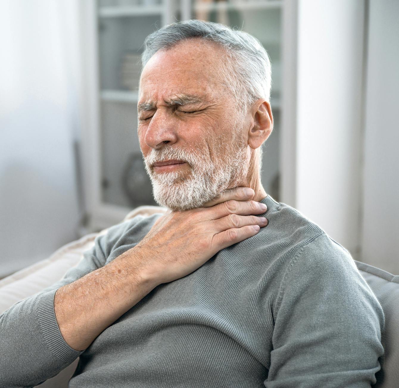 man touching his throat in discomfort