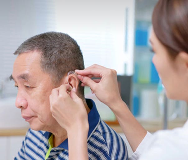 doctor fitting a hearing aid on a patient