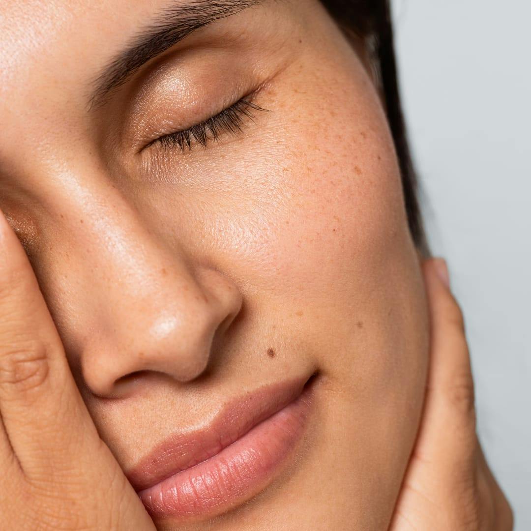 woman with eyes closed holding face