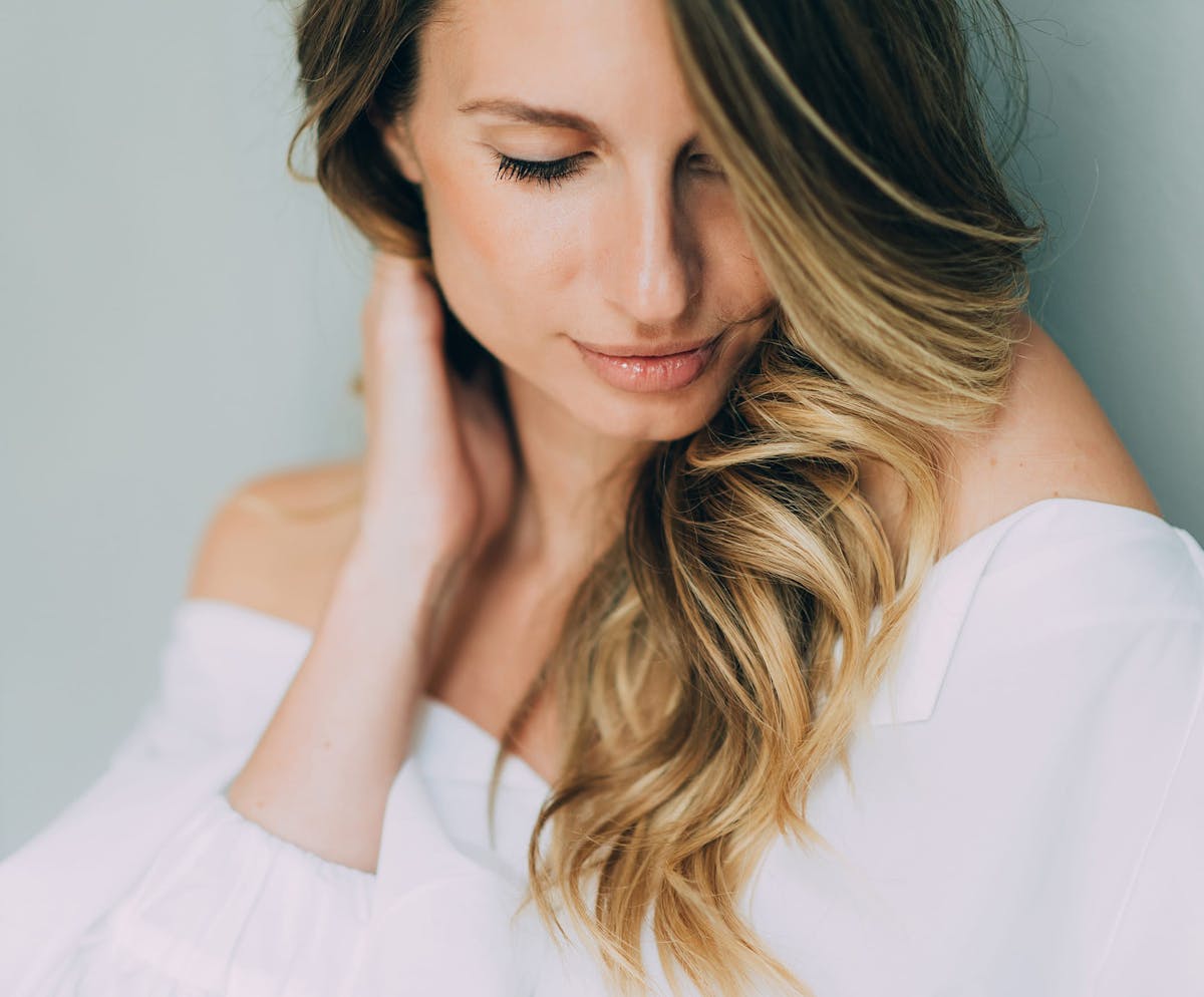 Woman glancing down while brushing hair back