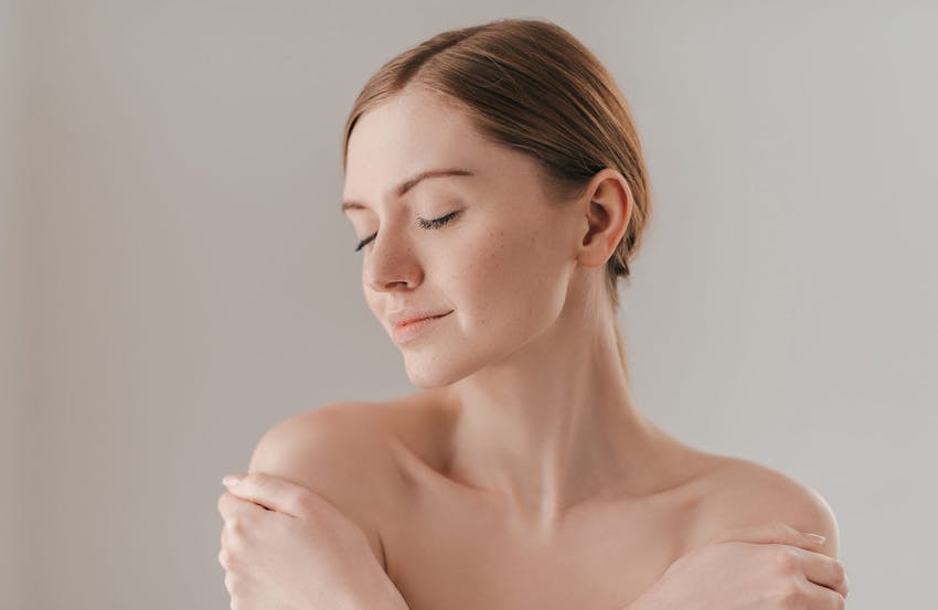 Woman smiling and holding shoulders
