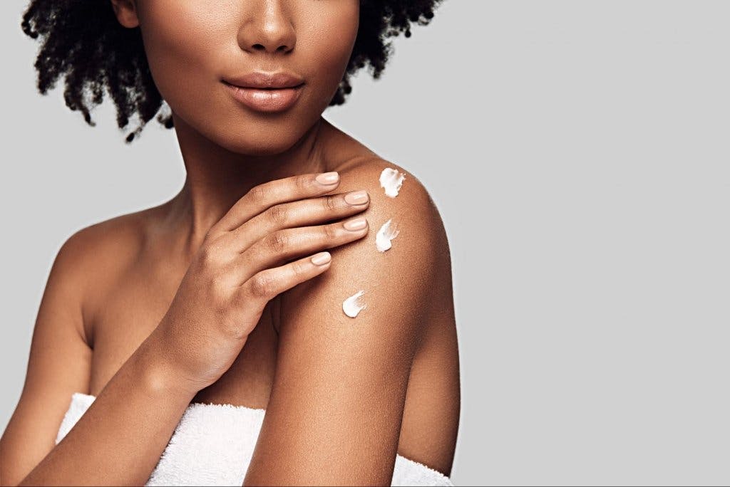 Woman applying cream to shoulder