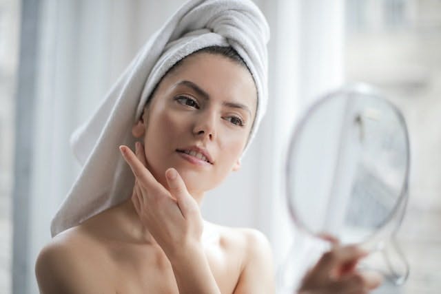 woman looking at herself in a handheld mirror