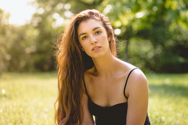 woman with very long hair sitting outside in the grass
