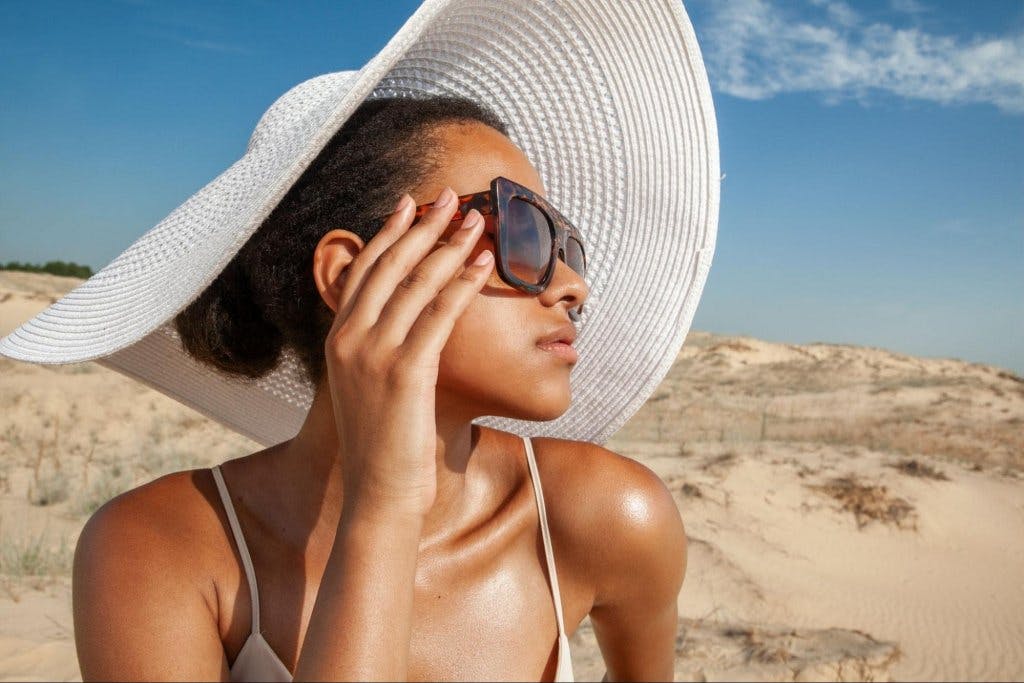 woman at the beach in a big sun hat and sungalsses