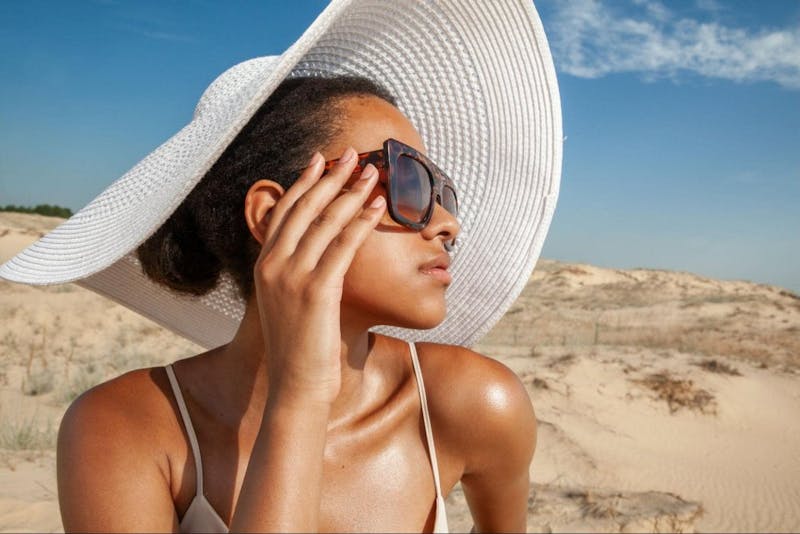 woman at the beach in a big sun hat and sungalsses
