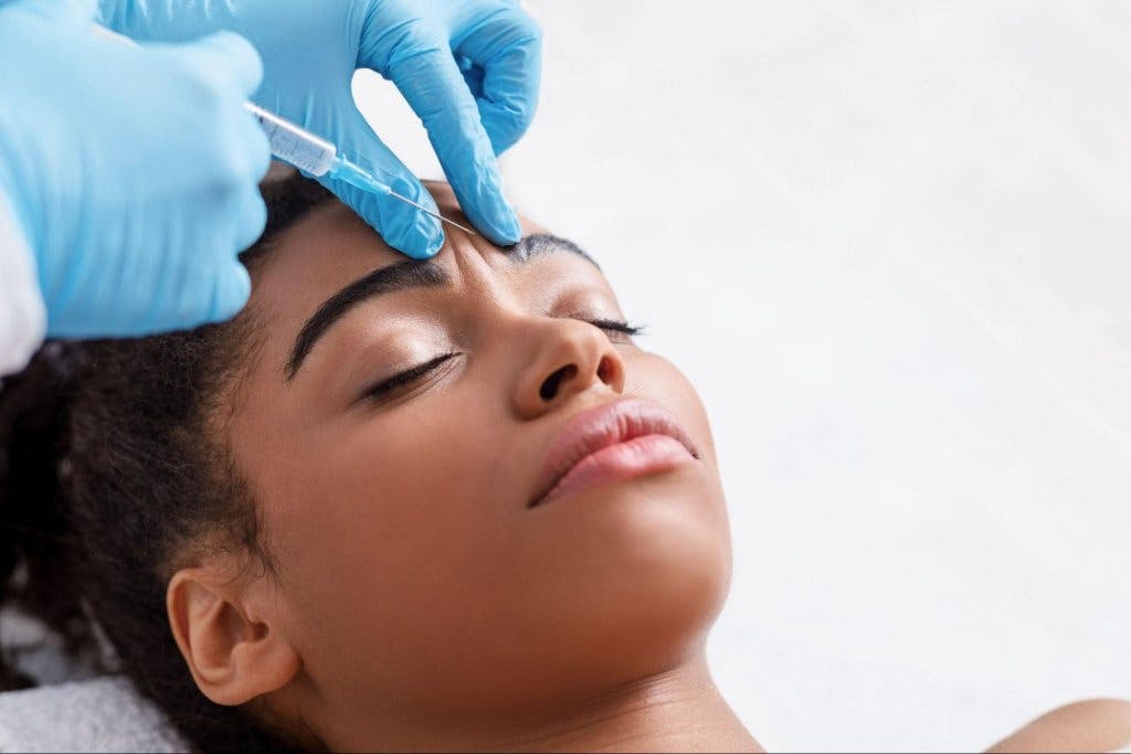 woman getting an injectable treatment between her eyebrows