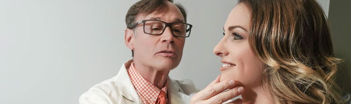 plastic surgeon looking at female patient's face
