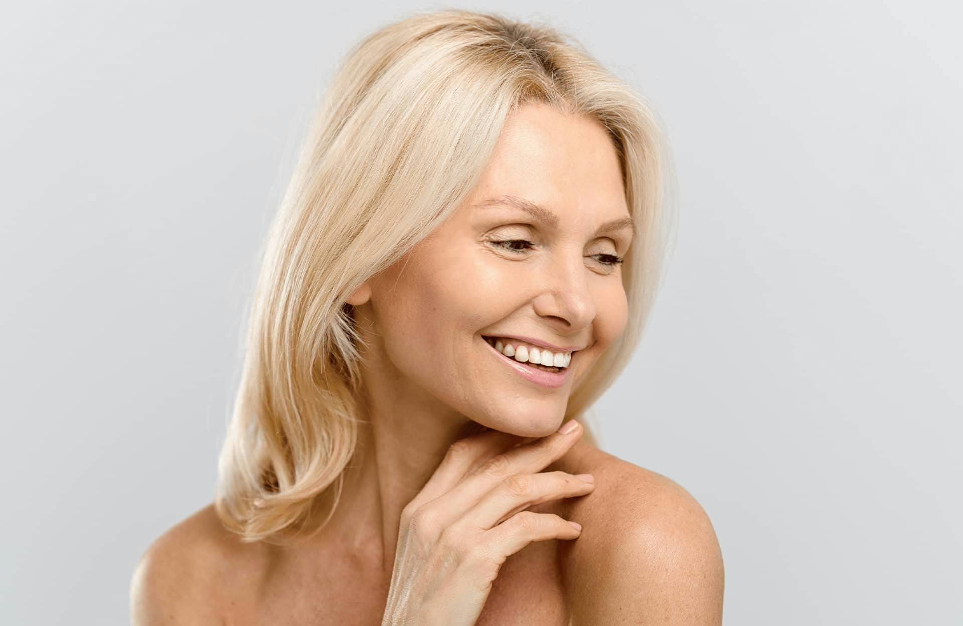 woman with blonde hair looking down to her left smiling