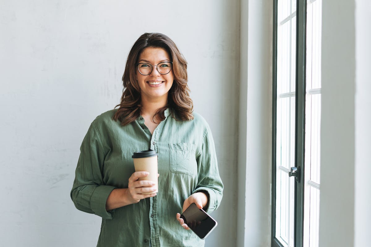 Happy Woman with a latte and phone in her hand
