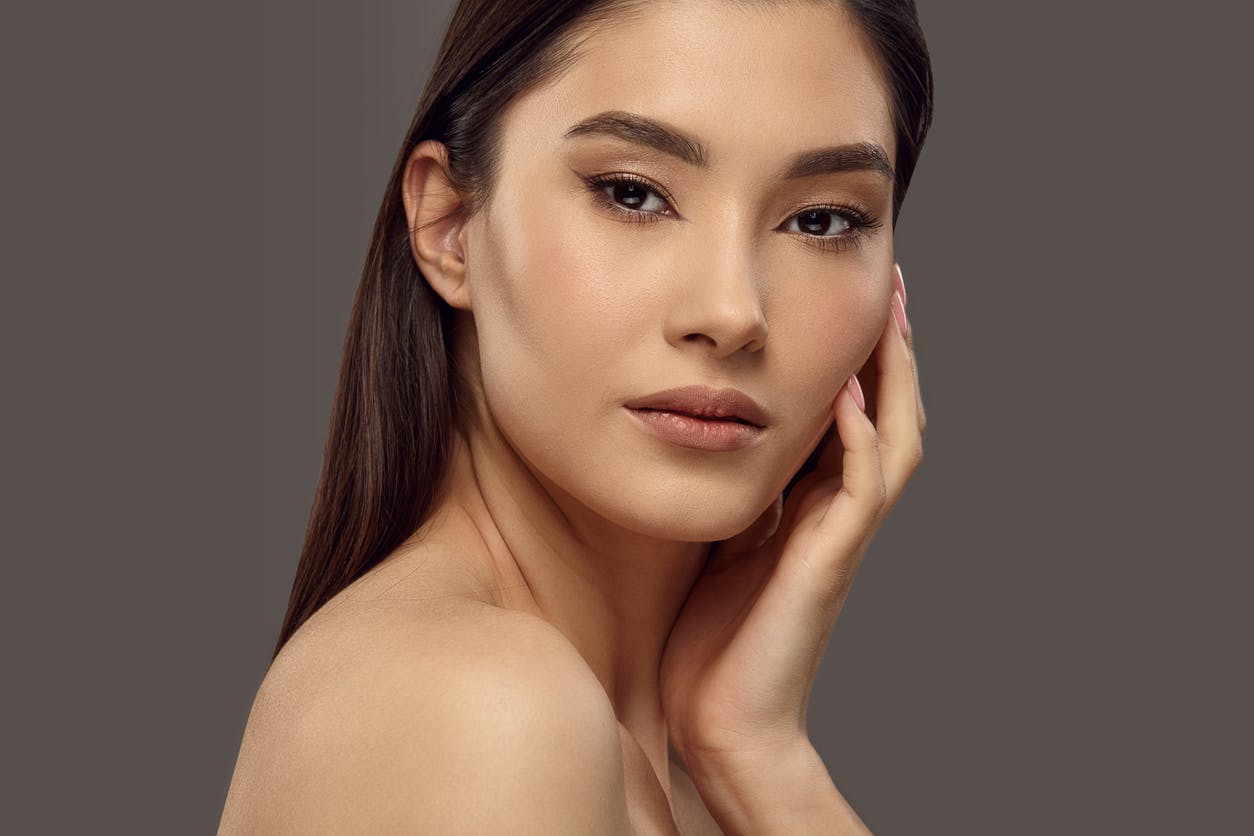 Closeup portrait of beautiful young woman with healthy flawless skin, looking to camera