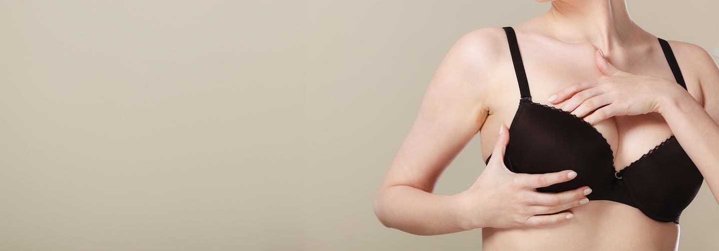 woman clothed in bra self-inspects right breast