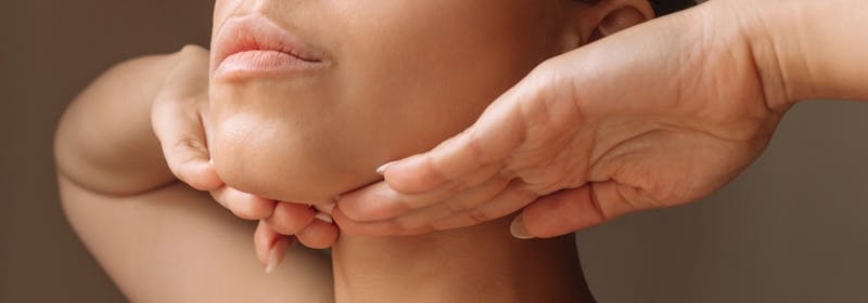a woman holds her hands beneath her chin