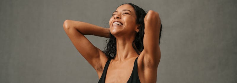 happy woman with lean arms holding hands behind her head